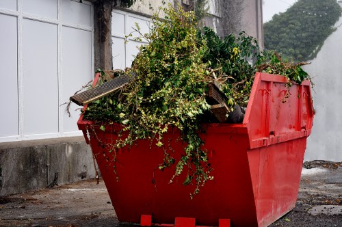 Builders removing garden waste into a large skip